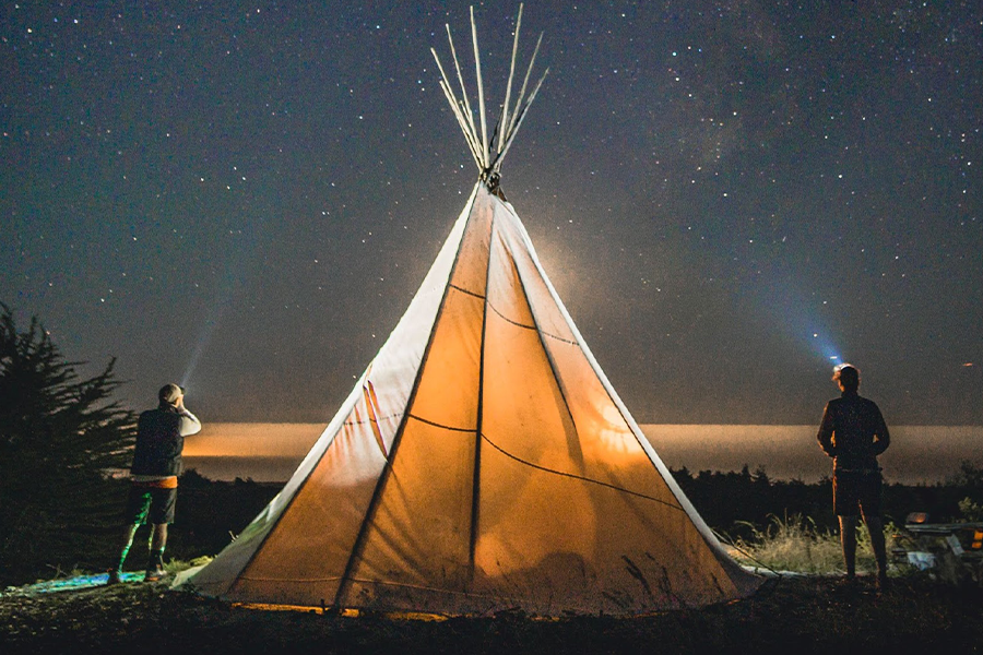 Due persone in piedi accanto alla tenda durante la notte