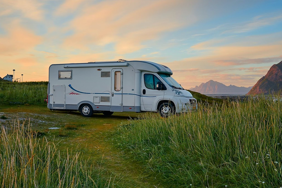 Camper bianco sul campo di erba verde durante il giorno