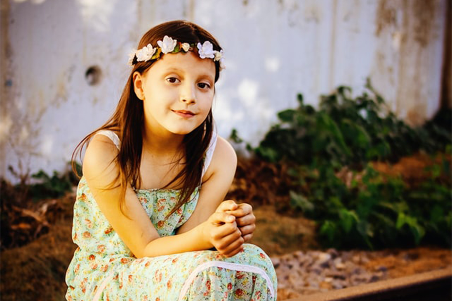 Ragazza in maxi vestito floreale che si siede sulla piattaforma di legno