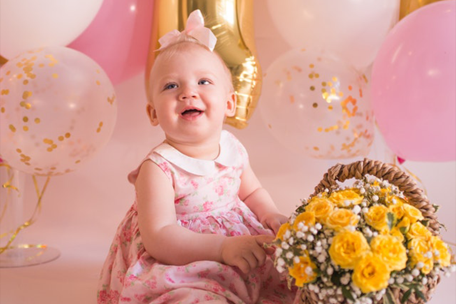 Bambina in un vestito rosa che si siede sul pavimento con un cesto di fiori