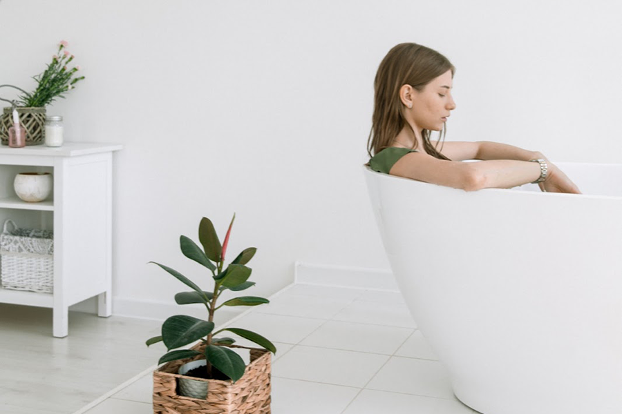 Femme dans une baignoire à côté d'une plante