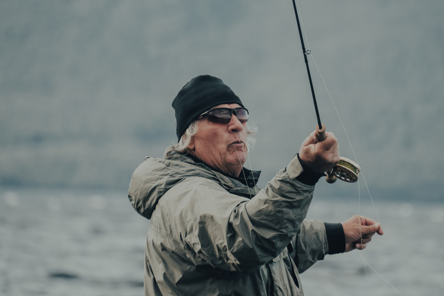 Idoso pescando vestindo um capuz de pesca cinza