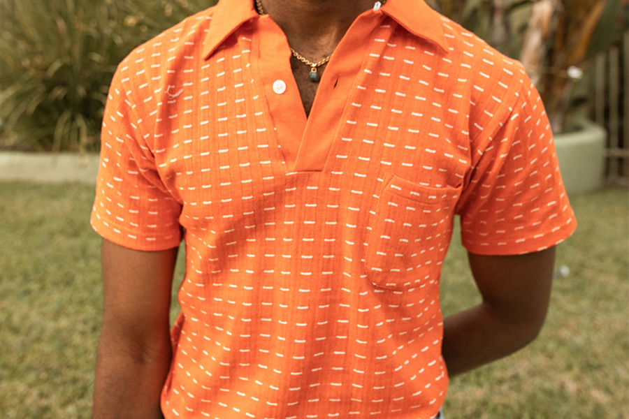 Homme en polo classique orange avec un pantalon gris