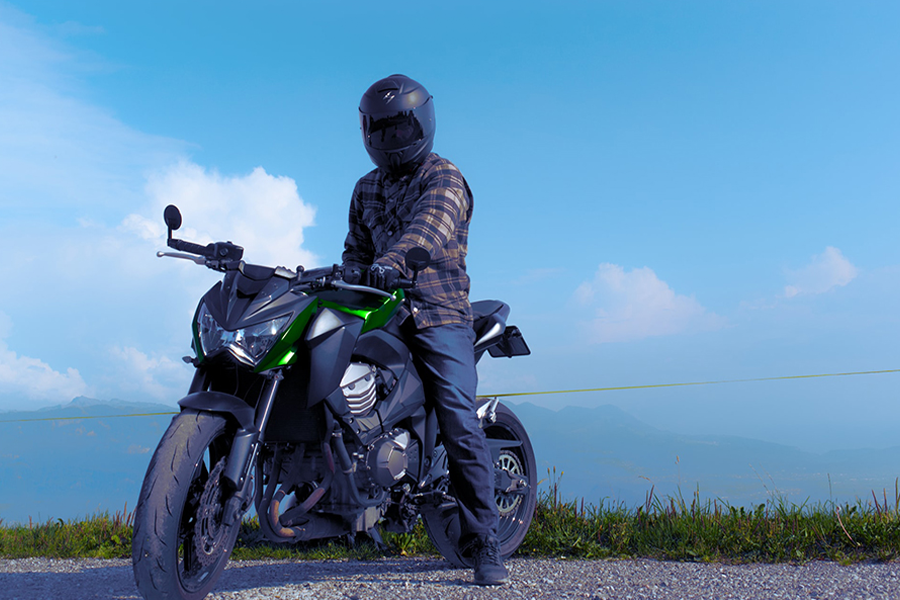 Motociclista sentado em uma motocicleta enquanto balança uma camisa blindada