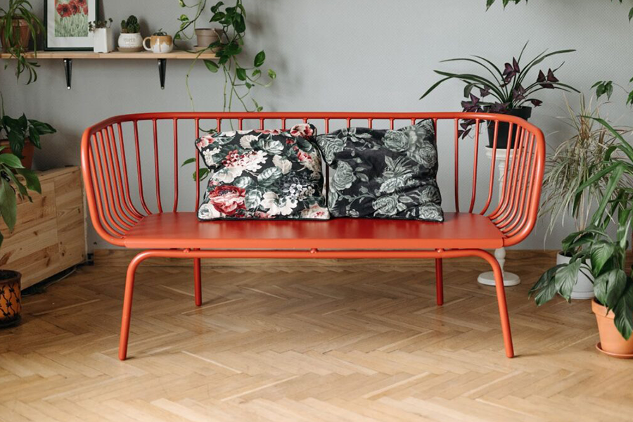 An elegantly painted aluminum outdoor sofa with two patterned pillows