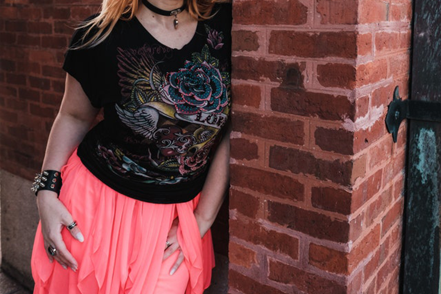 A woman wearing a pink asymmetrical skirt and black top