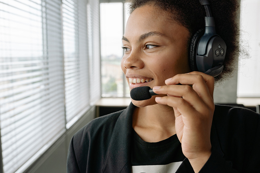 Lächelnde Dame, die das Mikrofon des Gaming-Headsets zur Kommunikation nutzt