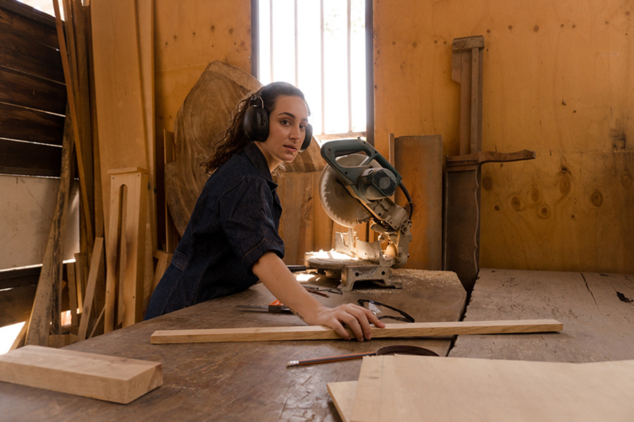 Donna con occhiali protettivi in ​​posa con una sega per legno