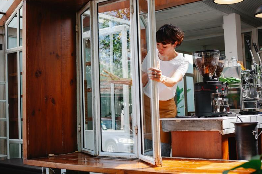 Barista kahve dükkanında beyaz bir katlanır pencere açıyor