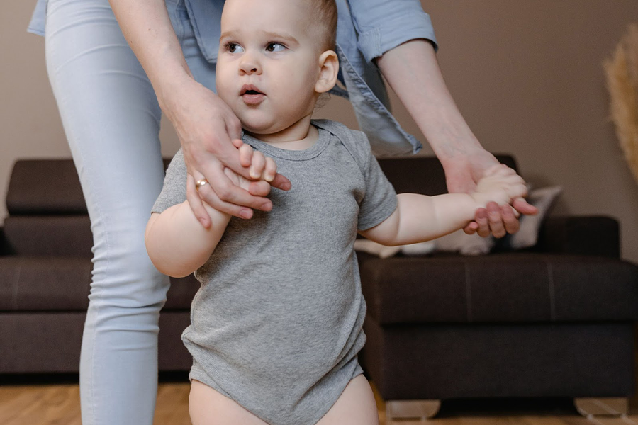 グレーのテリータオルの上で母親と一緒にポーズをとる幼児