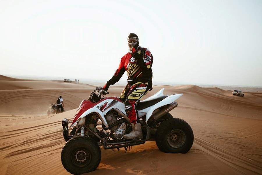 Homem de terno vermelho de moto posando em um ATV