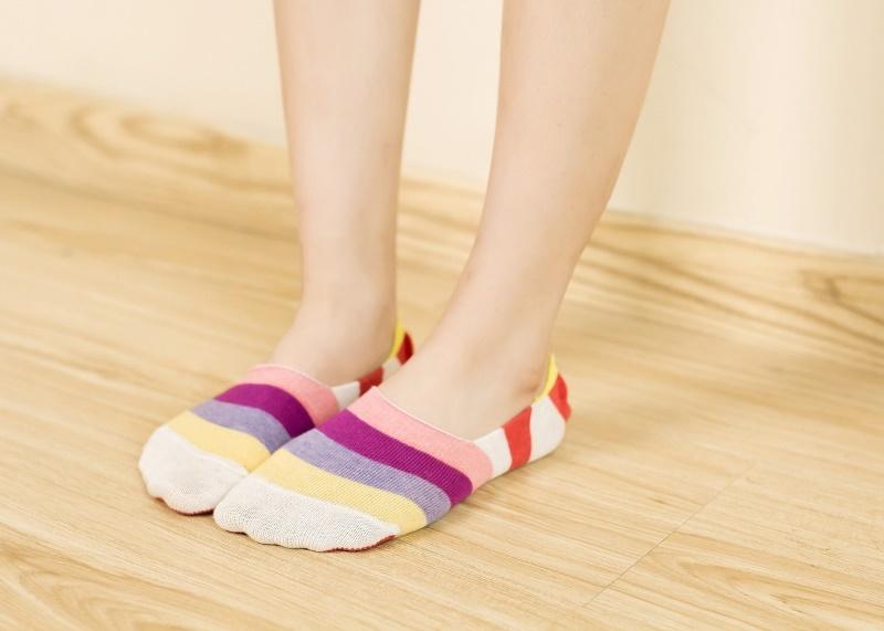 Pieds portant des chaussettes invisibles à rayures colorées