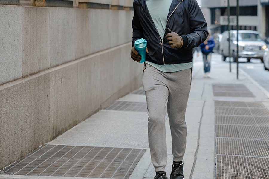 Uomo di mezza età che fa jogging per strada con pantaloni da jogging grigi intelligenti