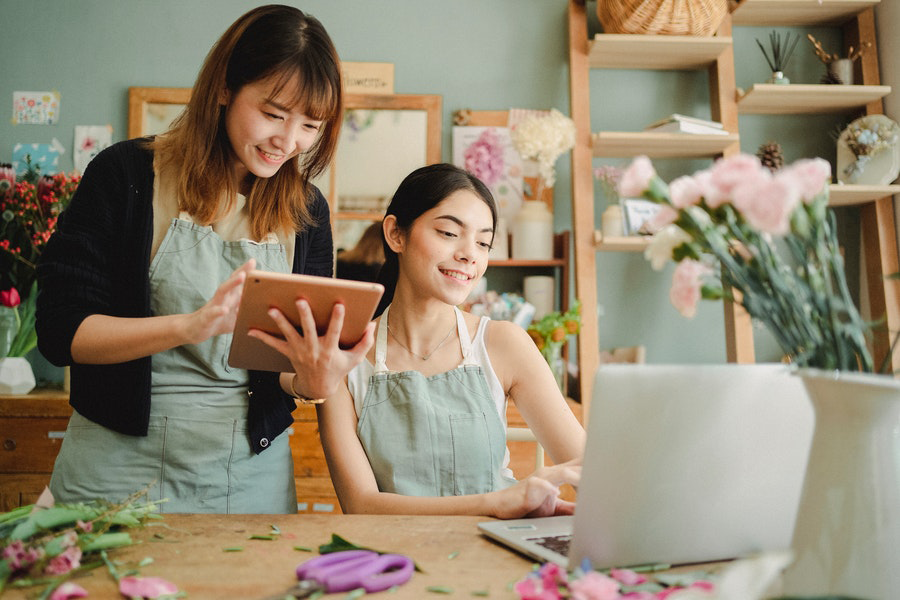 Dua wanita multiras tersenyum dan bekerja dengan gadget