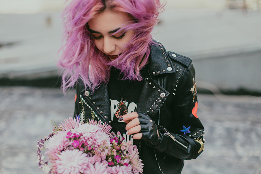 Dame aux cheveux roses portant une veste noire avec plusieurs logos