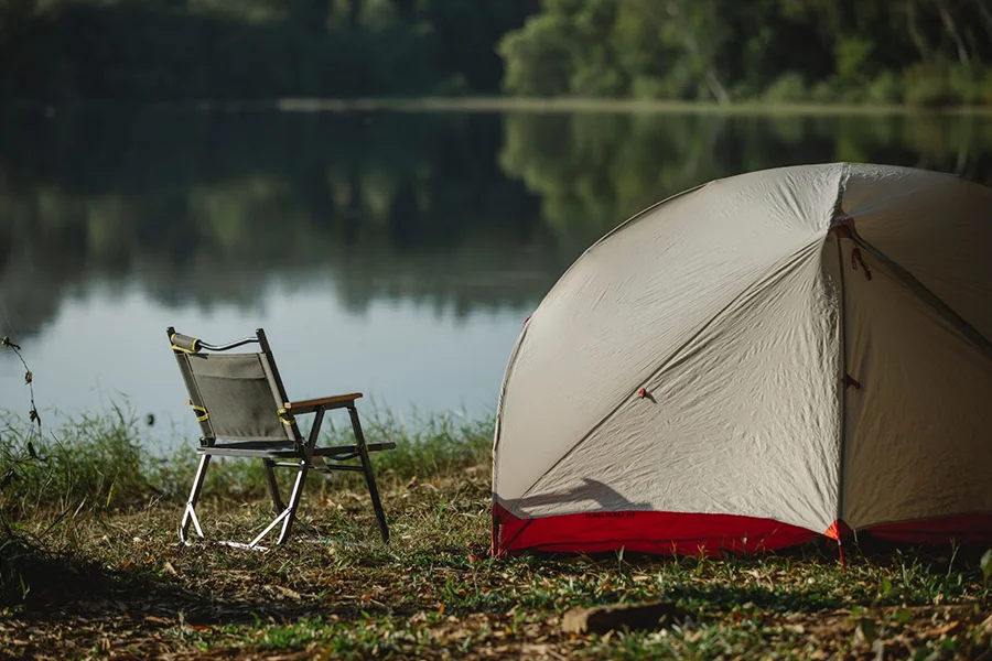 Une chaise de camping pliable à côté d'une grande tente