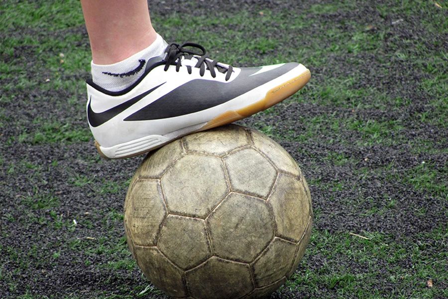 Un joueur de football plaçant une chaussure de gazon sur un ballon de football