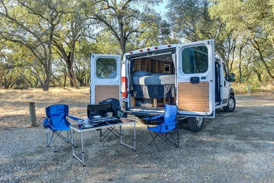 Cadeiras de campismo dobráveis ​​azuis montadas do lado de fora de uma autocaravana