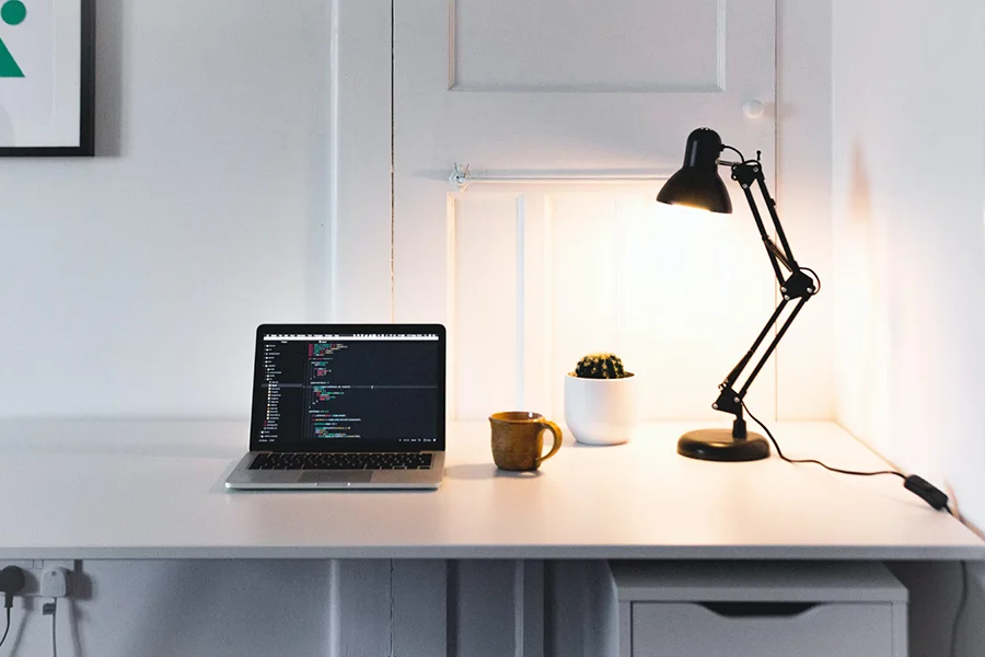 Lampe de bureau et ordinateur portable dans une salle blanche