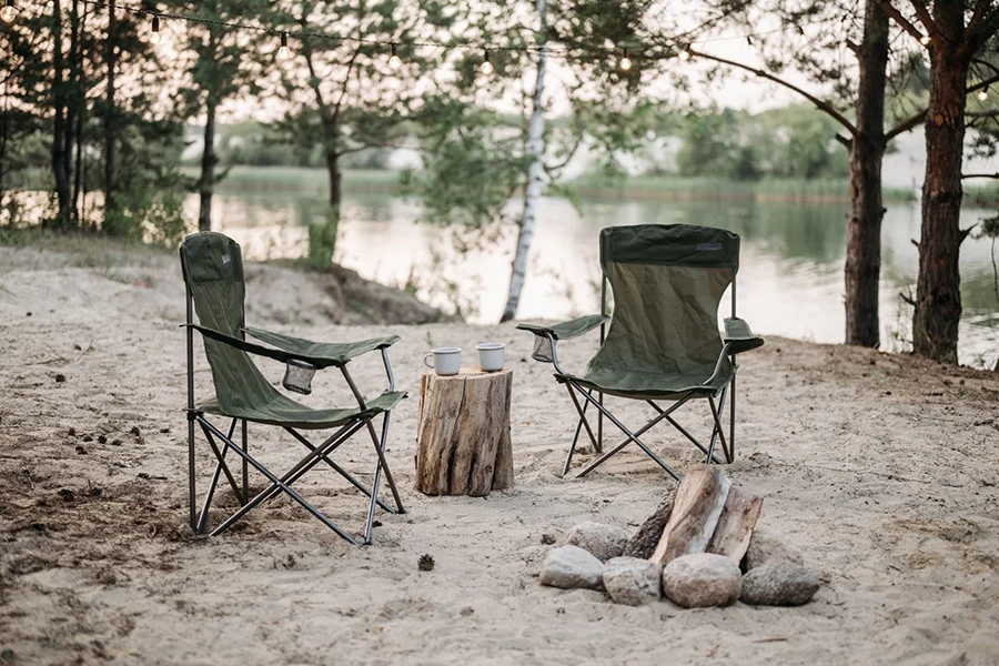 Deux chaises de camping pliables à côté d'un feu de camp en plein jour