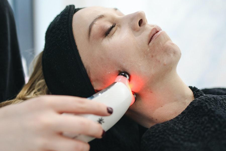 Uma mulher recebendo tratamento facial usando um dispositivo de alta tecnologia