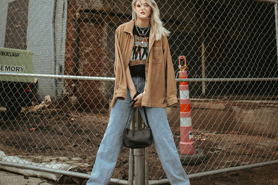 Hermosa dama rubia meciendo jeans sueltos y chaqueta marrón