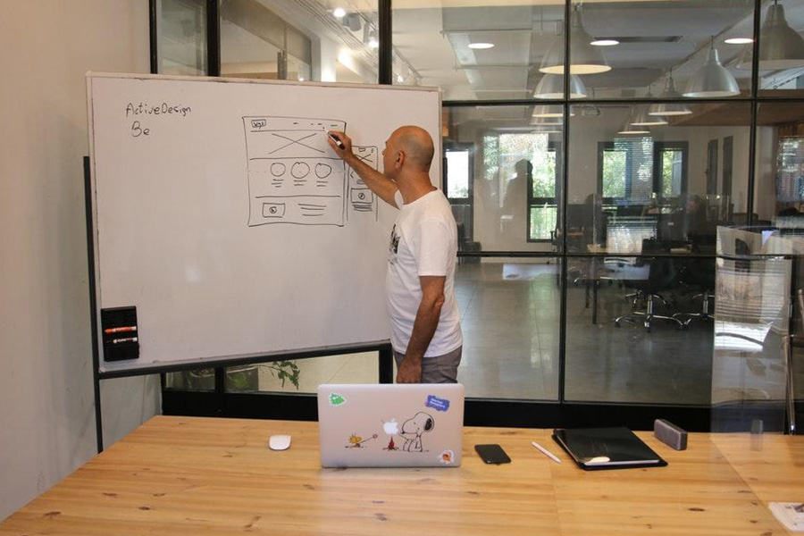 Mann in einem weißen bedruckten T-Shirt schreibt auf ein Whiteboard