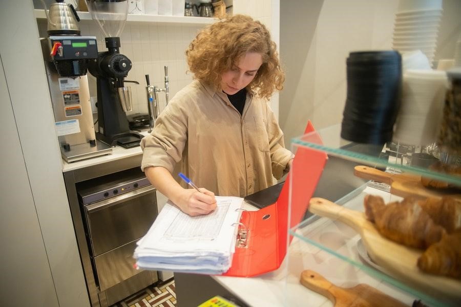 Femme en haut marron vérifiant les registres d'inventaire