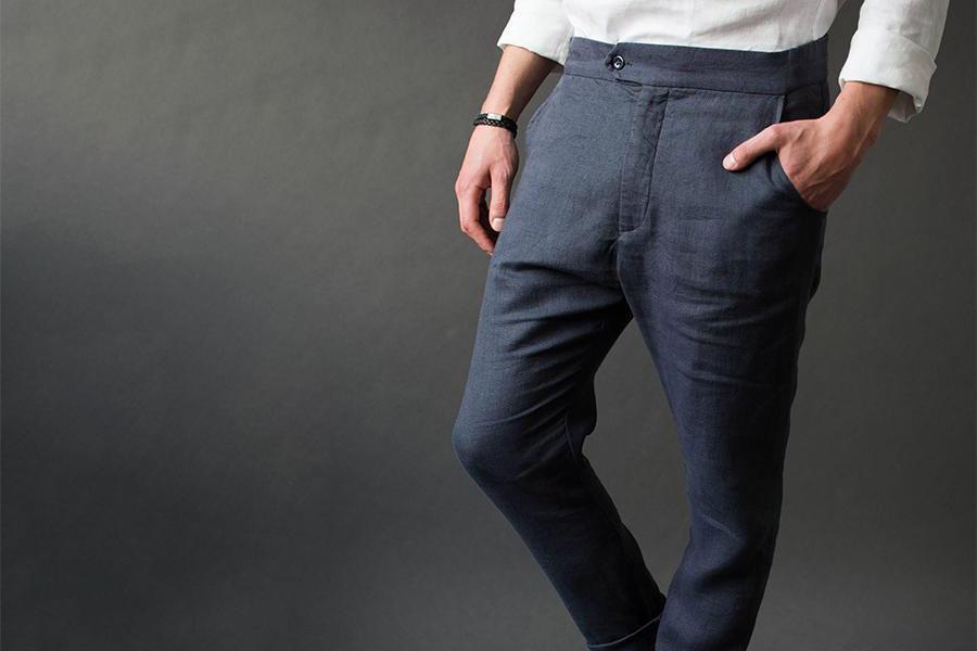 Un uomo che indossa pantaloni affusolati blu scuro mentre si appoggia