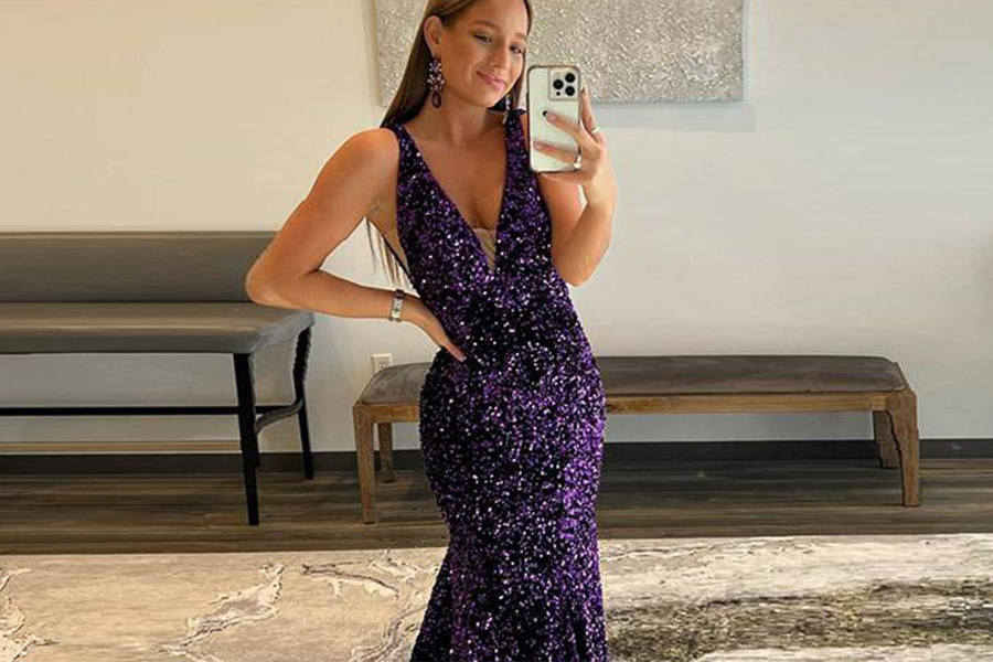 A woman wearing a nipped-in glittery purple waist dress