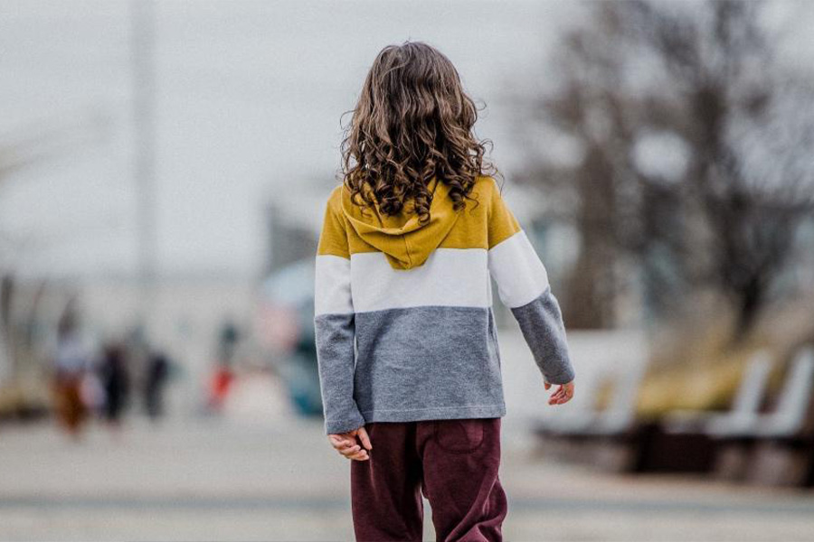 Ragazza con una felpa multicolore e pantaloni marroni