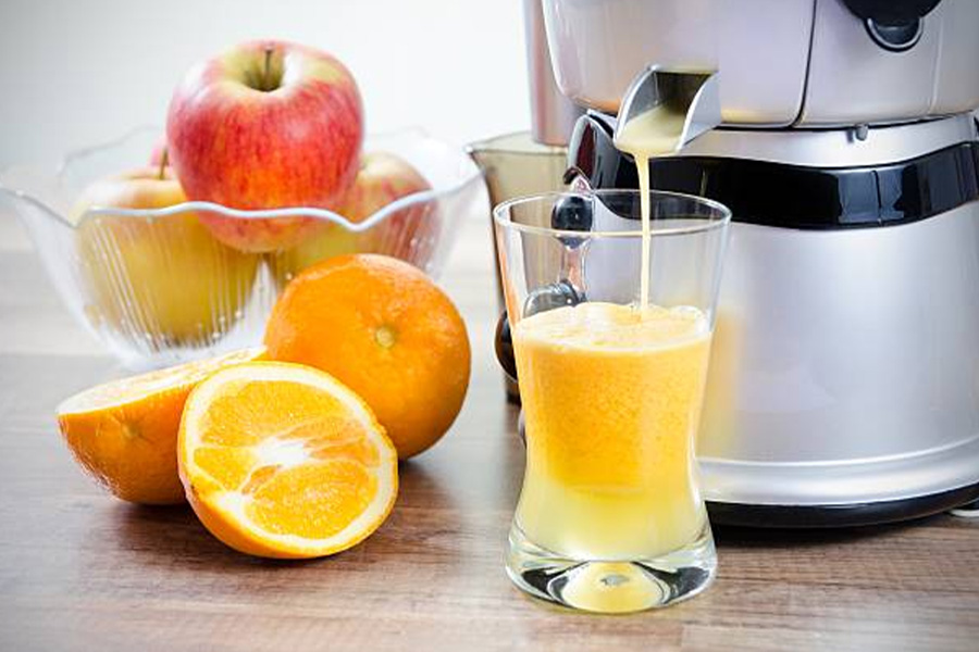 Máquina de sucos derramando suco fresco de laranja e maçã