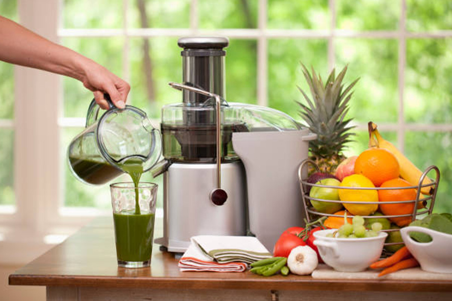 Grand presse-fruits avec verre de smoothie vert versé