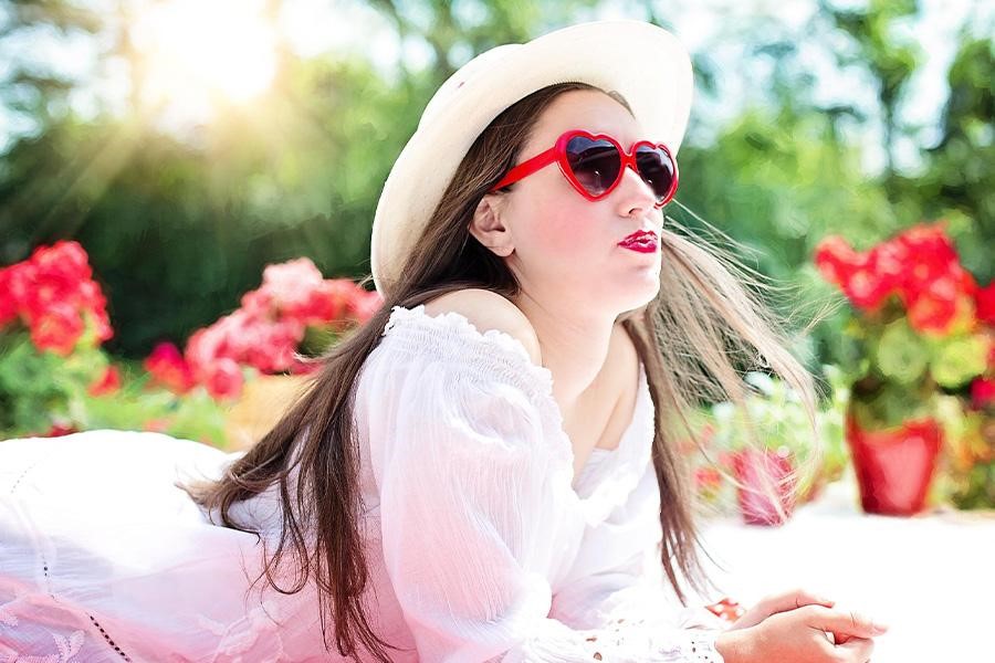 Teenager-Mädchen mit roter Sonnenbrille und weißem, transparentem Kleid