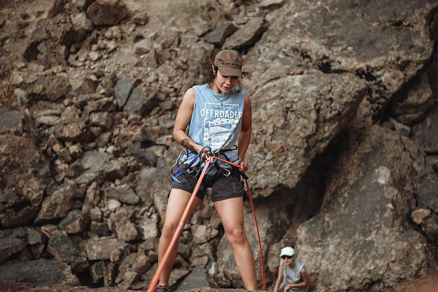 Frau beim Wandern in einem hellblauen Tanktop und schwarzen Shorts