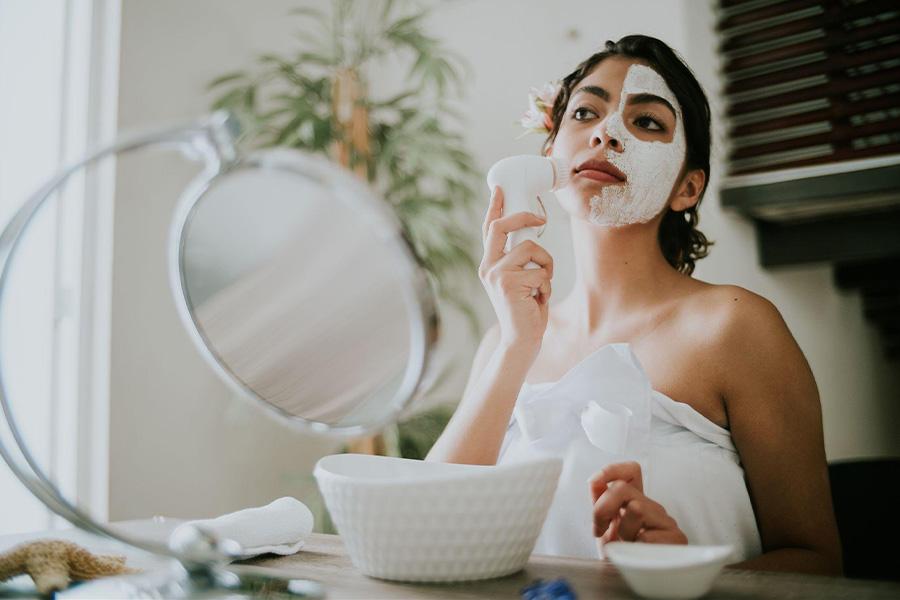 Mulher usando uma escova de limpeza facial