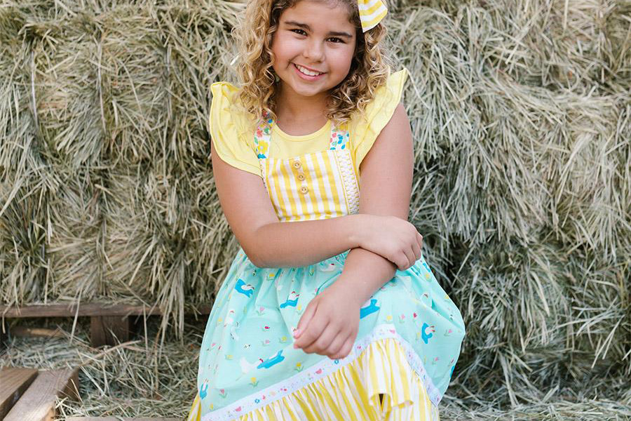 Niña luciendo un vestido a cuadros de felpa amarilla y azul