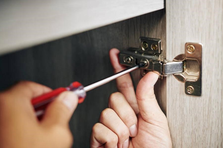 A cabinet hinge being screwed into the cabinet