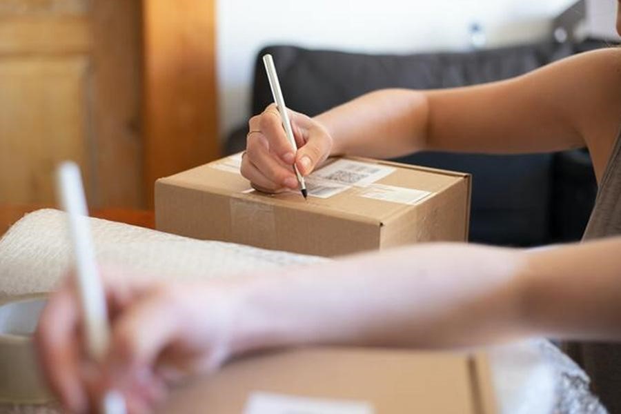 Una persona escribiendo en cajas de cartón marrón.