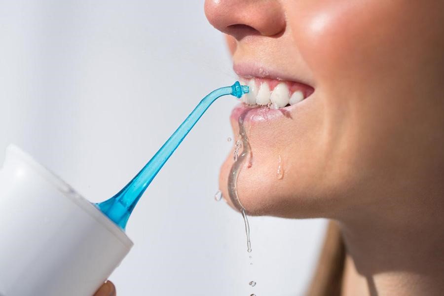 A woman using a portable water flosser