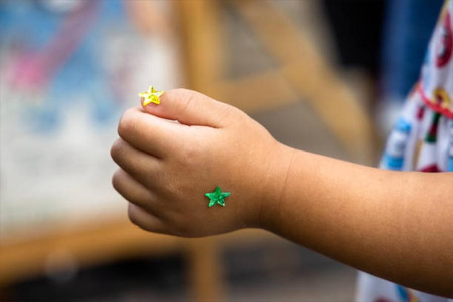 Niño con dos pequeñas pegatinas de estrellas brillantes en la mano