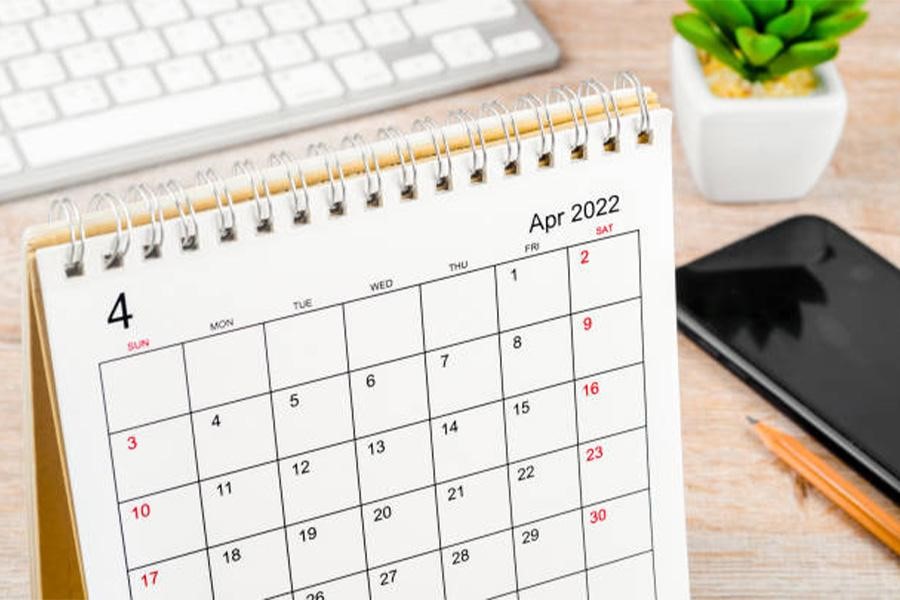 Calendario de escritorio abierto hasta abril junto a laptop y smartphone