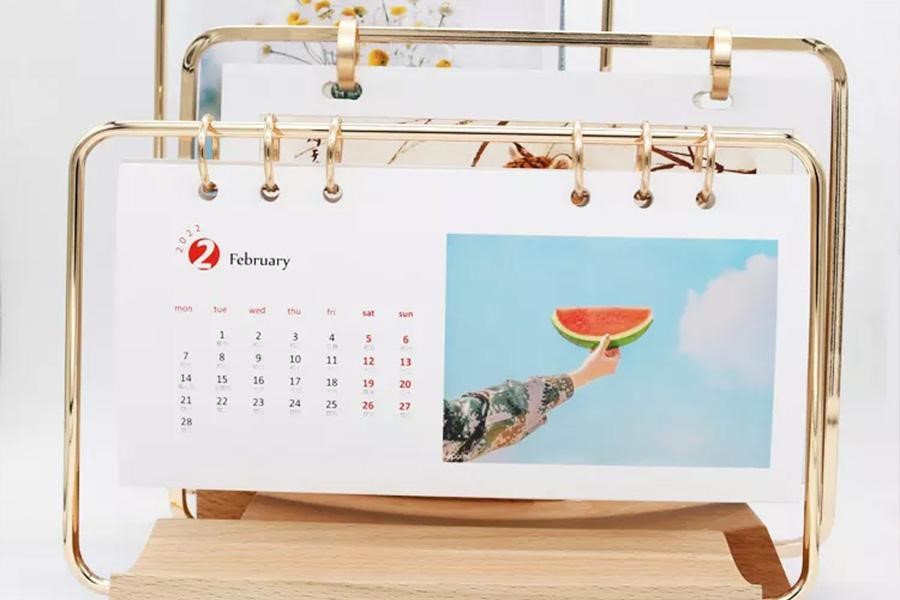 Calendario de escritorio con soporte dorado y de madera abatible sobre la mesa