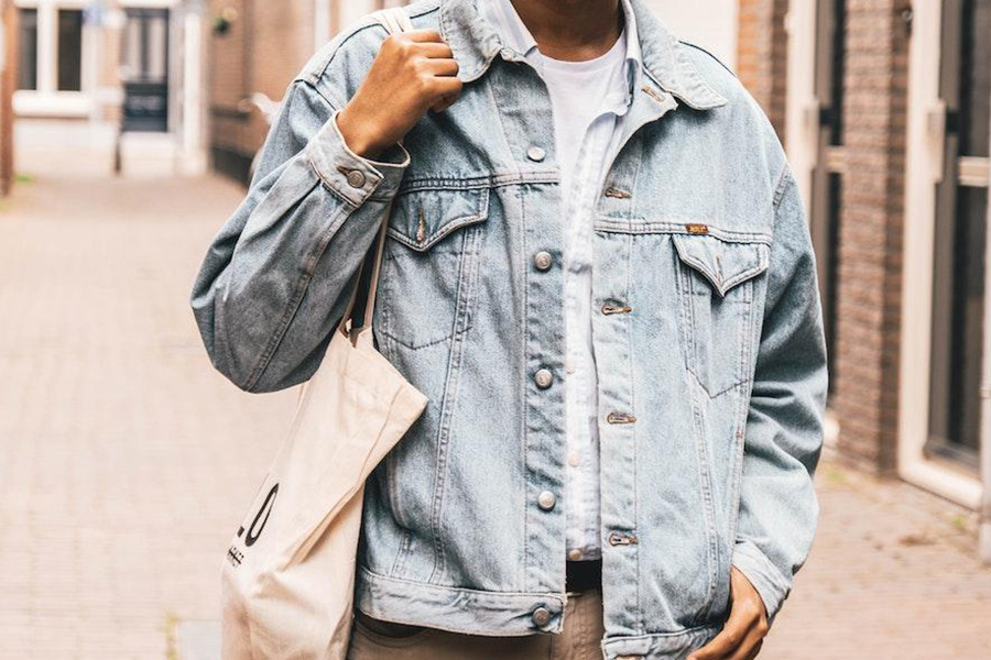 Homem balançando jaqueta jeans com botões grandes