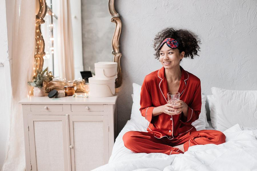 Mulher balançando um pijama vermelho em uma cama