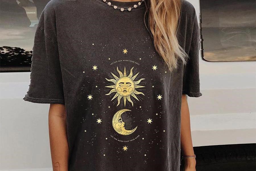 Femme berçant un haut surdimensionné avec un motif soleil et lune