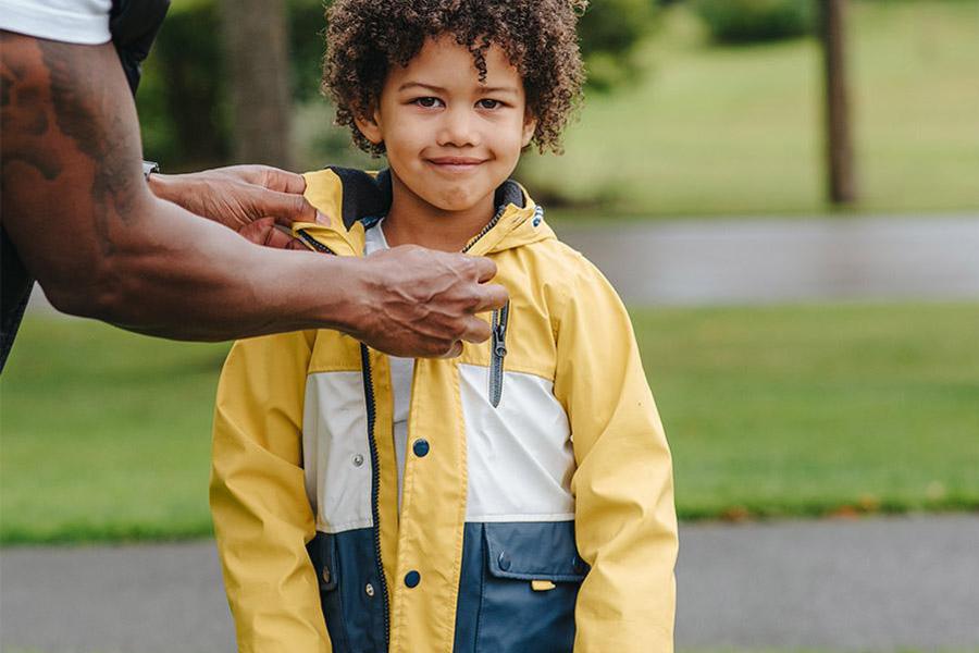 Anak laki-laki mengenakan jaket utilitas kuning dan biru