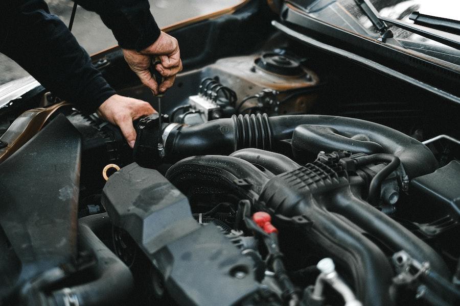 Un hombre revisando el motor con herramientas