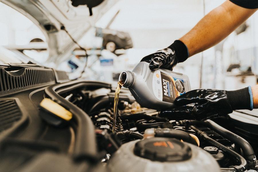 Un hombre rellenando el aceite de un motor.