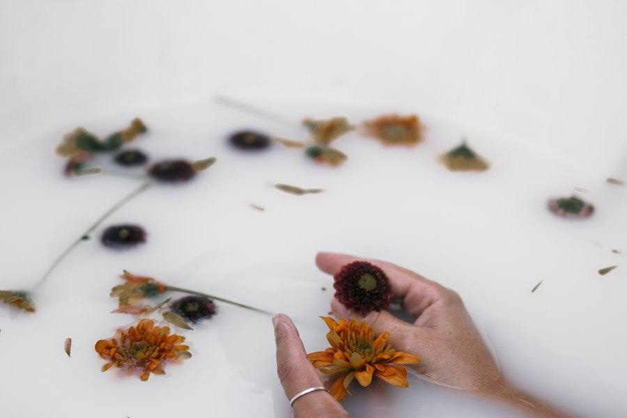 Donna anonima che tiene fiori in un bagno di latte